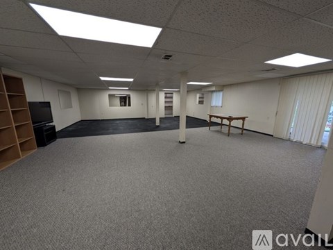 A spacious office room with a carpeted floor and a television on the left side.