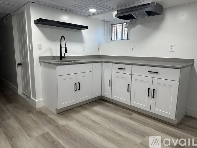 A kitchen with white cabinets and a grey countertop.