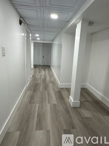 A long hallway with wood flooring and white walls.