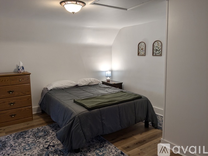 A bedroom with a bed, dresser, and two wall sconces.