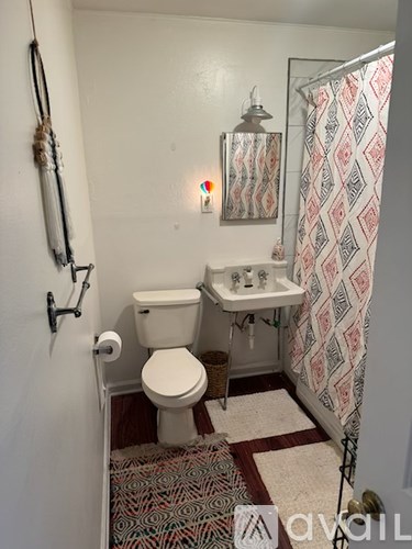 A bathroom with a toilet, sink, and shower curtain.
