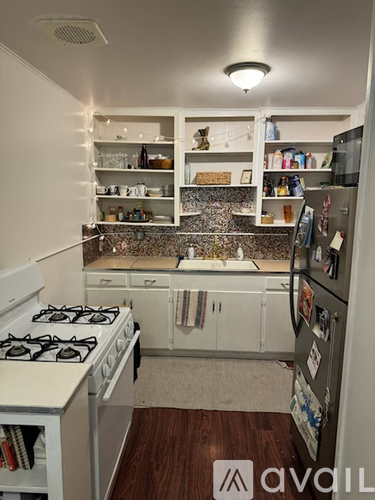 A kitchen with a white gas stove and a refrigerator with magnets on it.