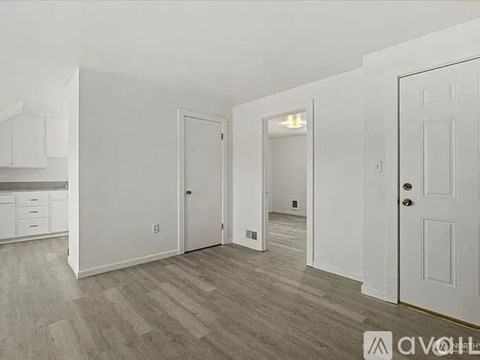 A white interior with a kitchen area to the left and a hallway to the right.