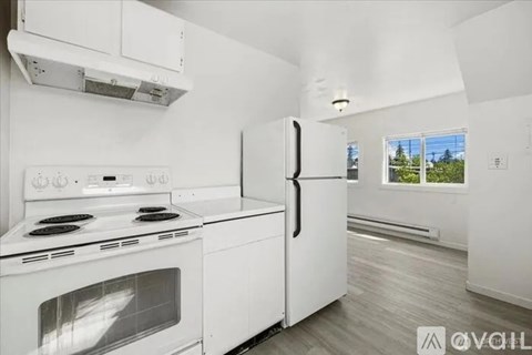A white kitchen with a stove, oven, and refrigerator.