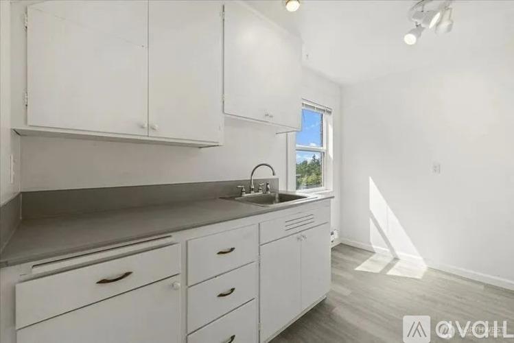 A kitchen with white cabinets and a window.