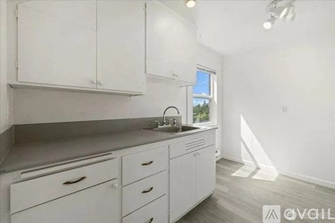 A kitchen with white cabinets and a window.