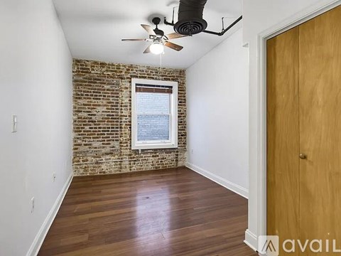 A room with a brick wall and a ceiling fan.