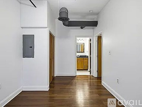 A long hallway with a door on the right and a vent on the ceiling.