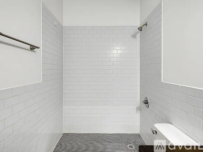A white tiled bathroom with a shower and a toilet.