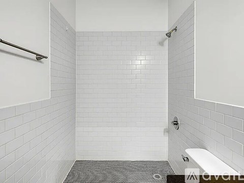 A white tiled bathroom with a shower and a toilet.
