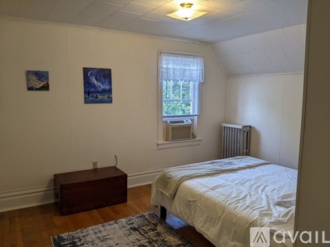 A bedroom with a bed, nightstand, and window.