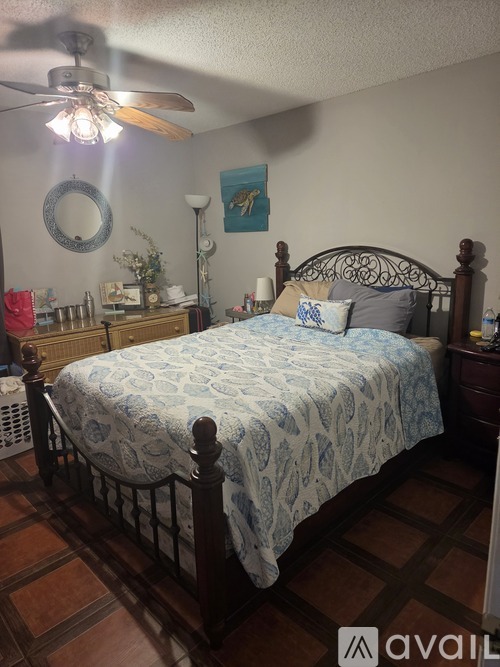 A bedroom with a bed, dresser, and ceiling fan.