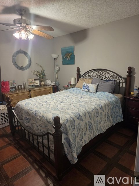 A bedroom with a bed, dresser, and ceiling fan.