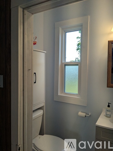 A bathroom with a toilet, sink and window.