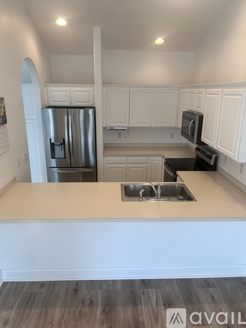 A kitchen with white cabinets and a stainless steel refrigerator.