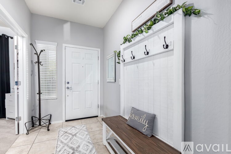 A hallway with a bench and a coat rack.
