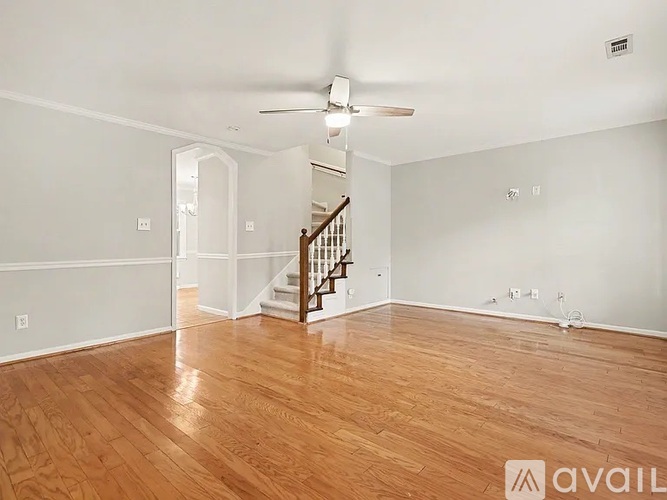 A spacious room with wooden flooring and a staircase.