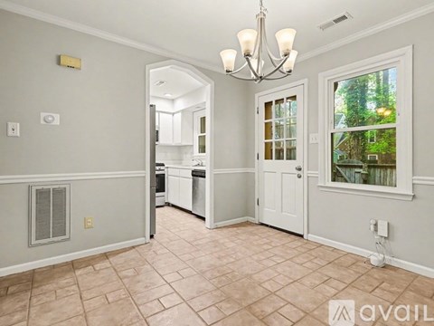 A well-lit kitchen with a chandelier and a window with a view of trees outside.