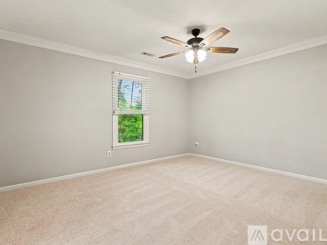 A room with a ceiling fan and a window with a view of trees.