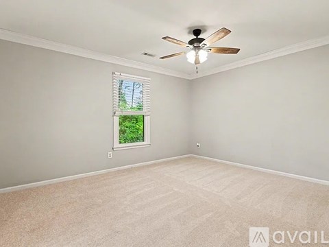 A room with a ceiling fan and a window with a view of trees.