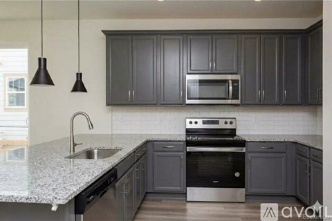 A kitchen with dark cabinets and a granite countertop.