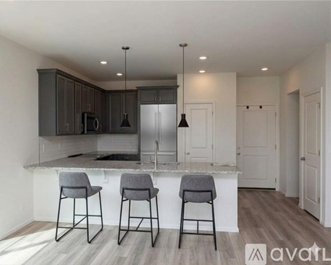 A kitchen with a bar area and three bar stools.