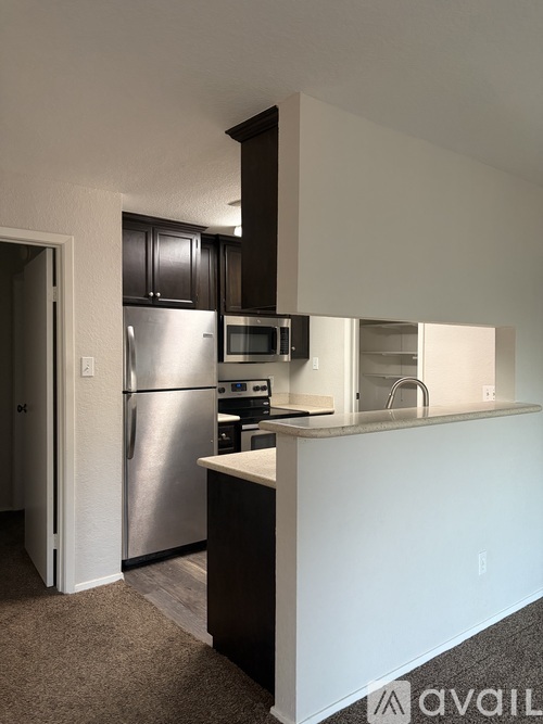 A kitchen with a refrigerator, microwave, and oven.