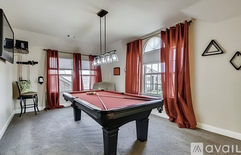 A pool table is in the middle of a room with a chair and a television.