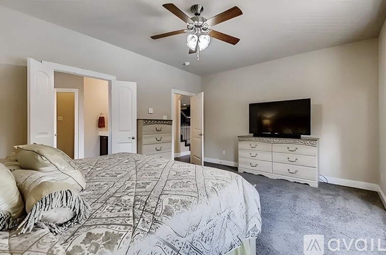A bedroom with a large bed and a television on a dresser.