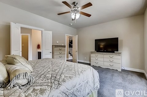 A bedroom with a large bed and a television on a dresser.