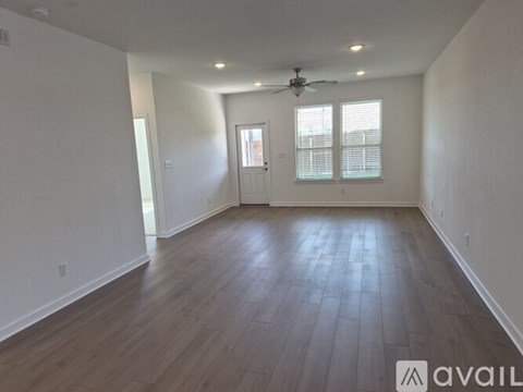 A spacious room with wooden flooring and a ceiling fan.