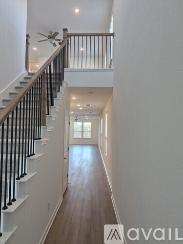 A long hallway with a staircase on the left and a door on the right.