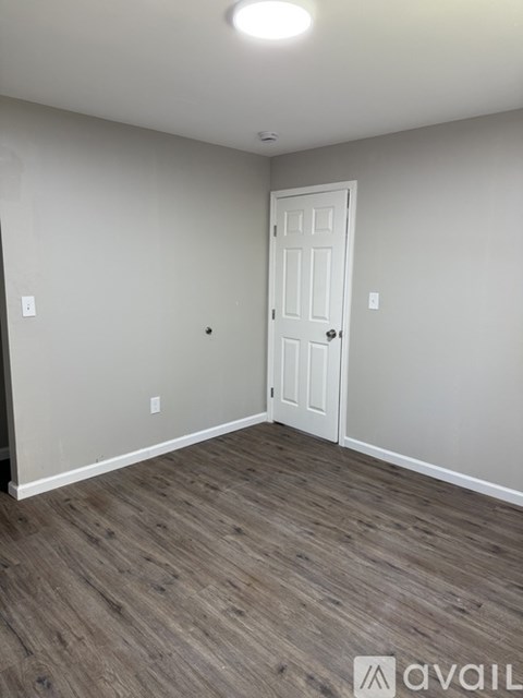 A room with a white door and wooden flooring.