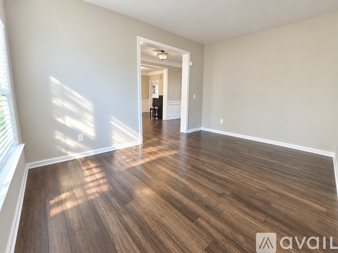 A room with wooden flooring and a doorway leading to another room.