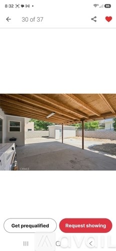 A wooden covered patio area with a white wall and a door.