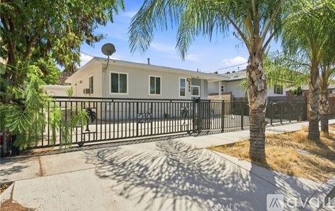 A house with a black gate and a palm tree in front.
