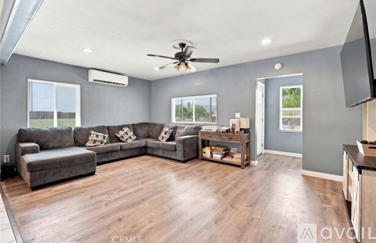 A spacious living room with a grey sofa set and a wooden floor.