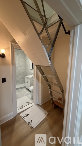 A ladder is leaning against a wall in a room with a box on the floor.