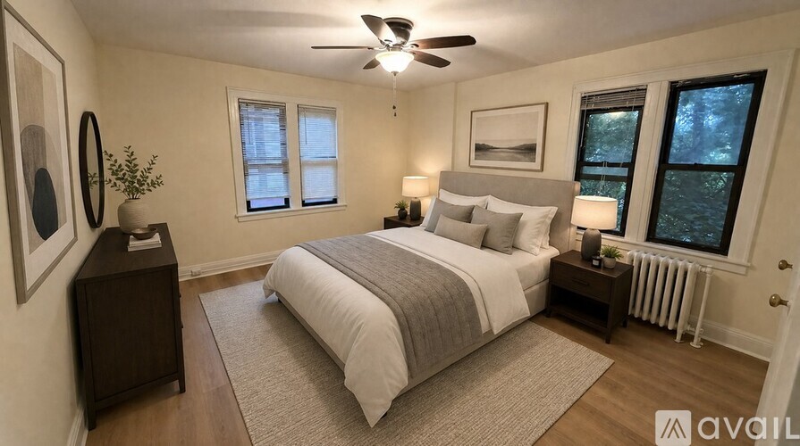A bedroom with a large bed, a ceiling fan, and a window with a view of trees outside.