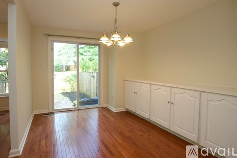 A room with wooden floors and white walls with a chandelier hanging from the ceiling.