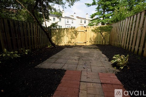 A backyard with a brick pathway and wooden fences.