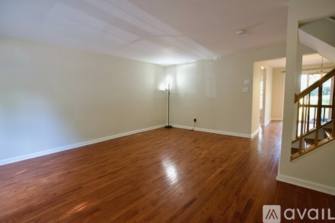 A room with wooden flooring and a staircase on the right side.