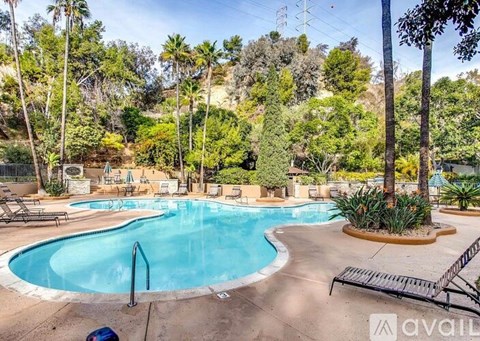 A large outdoor swimming pool surrounded by palm trees and lounge chairs.