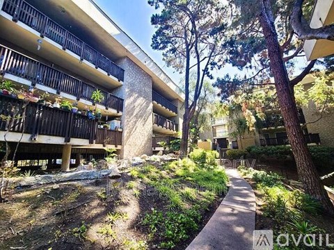 A pathway leads through a landscaped courtyard between two buildings.