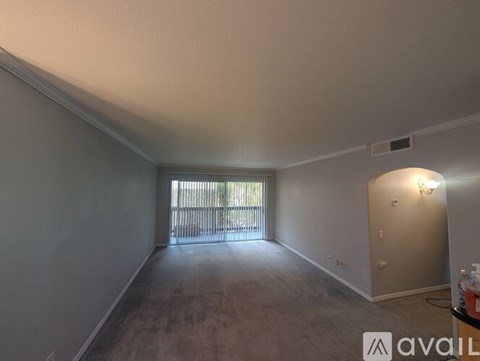 A room with a carpeted floor and a window with blinds.