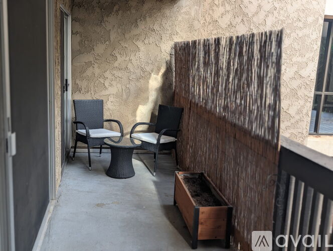 A patio with a wooden fence, two chairs, and a table.
