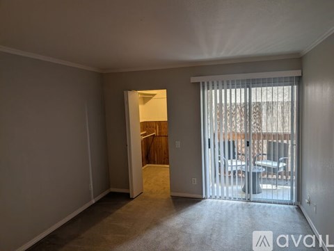 A room with a carpeted floor and a sliding glass door leading to a balcony.