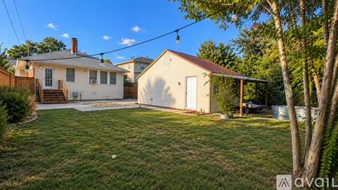 A house with a white exterior and a brown roof is surrounded by a grassy yard.