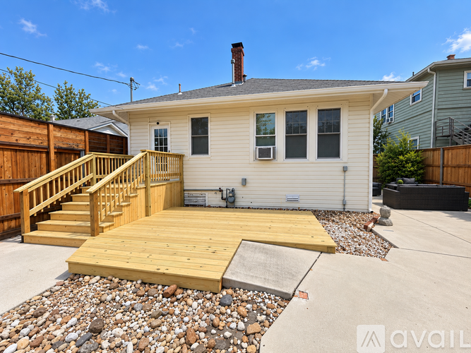 A house with a wooden deck and a gravel area in front.
