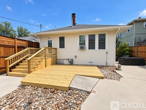 A house with a wooden deck and a gravel area in front.
